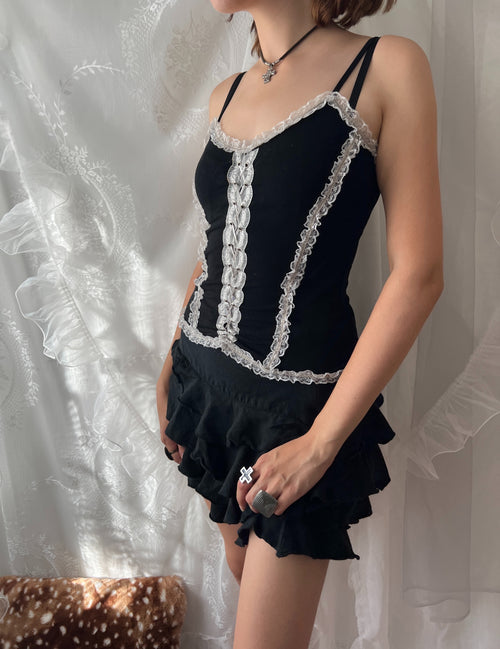 Black lace corset top with white lace trim and adjustable straps